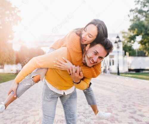 smiling-man-with-trendy-hairstyle-carrying-friend-piggyback-sunny-autumn-day_197531-5918