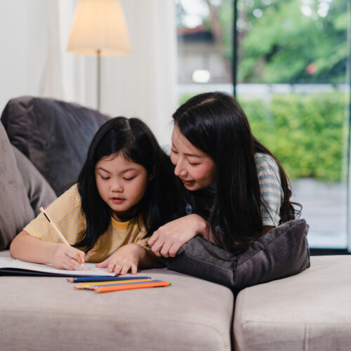 Asian middle-aged woman teach her daughter do homework and drawi